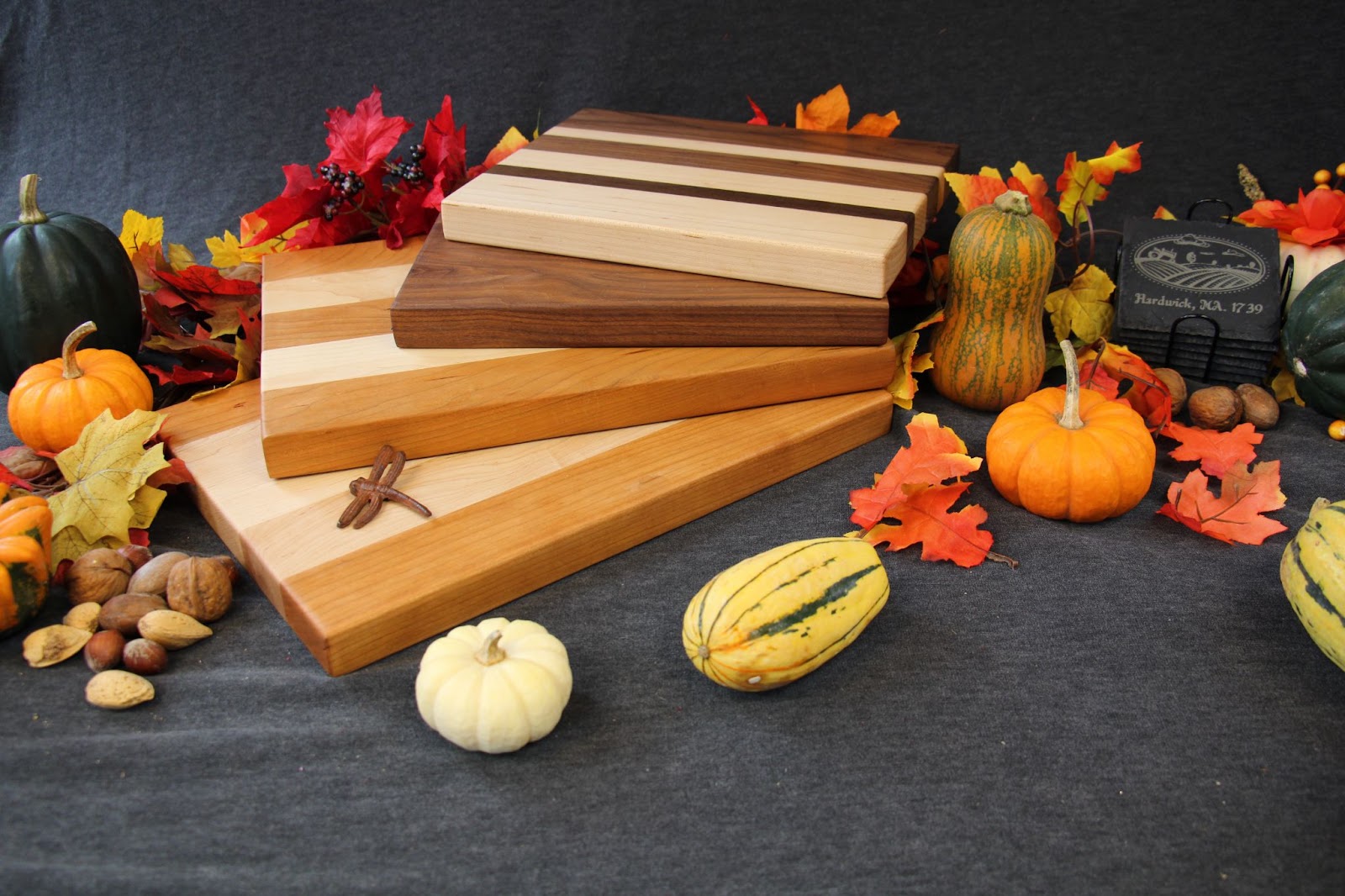 4 Wood Cutting and Charcuterie Boards surrounded by a number of real and fake gourds and fall foliage. Contest Image, Guess the Gourds to win.