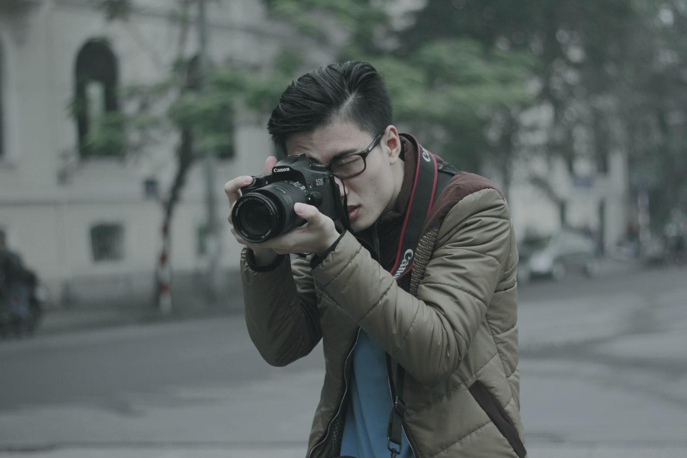 A man outside taking a picture on a camera - 5 Careers That Let You Be Creative At Work