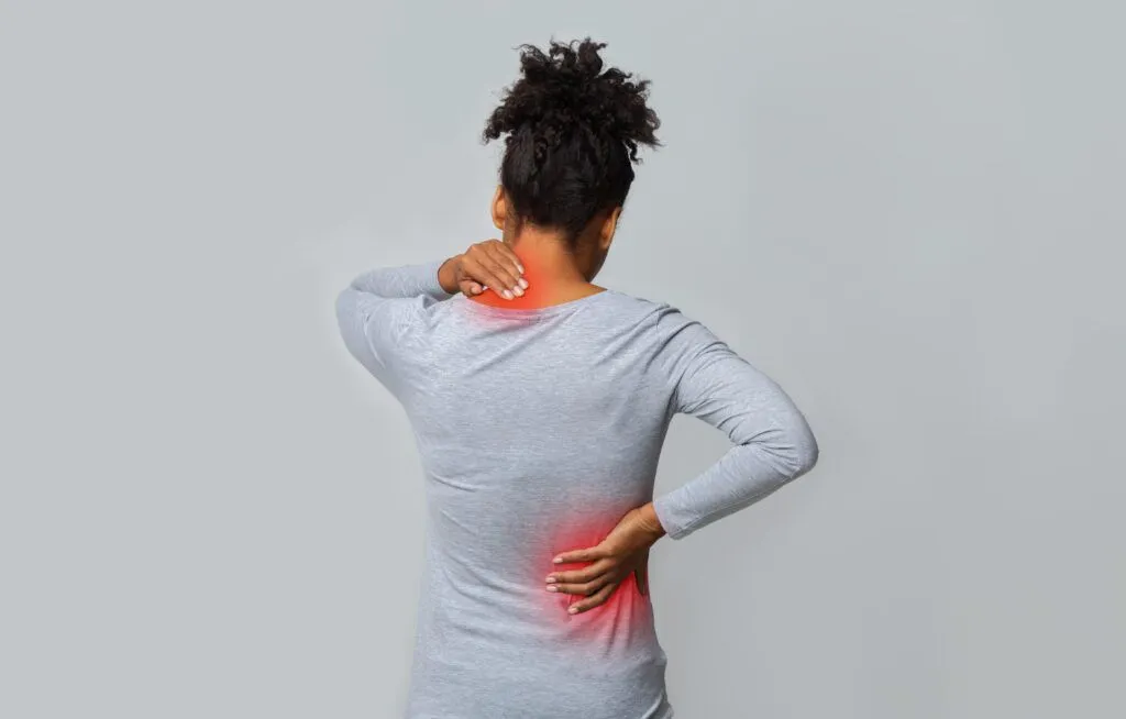 woman holding her neck and back where she is experiencing permanent nerve damage pain
