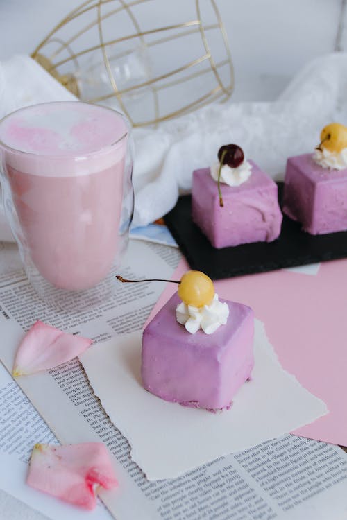Free Lavender Colored Glazed Petit Four Cake with Cherry and Pink Fruit Milkshake Stock Photo