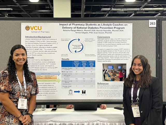 Hannah Reynolds and Natacha Rangel-Ribeiro standing if front of poster at A S H P Midyear conference