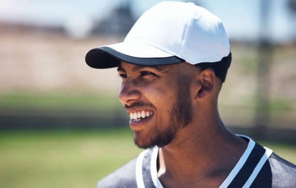 It's hard not to be happy playing baseball Shot of a young man playing a game of baseball baseball cap stock pictures, royalty-free photos & images