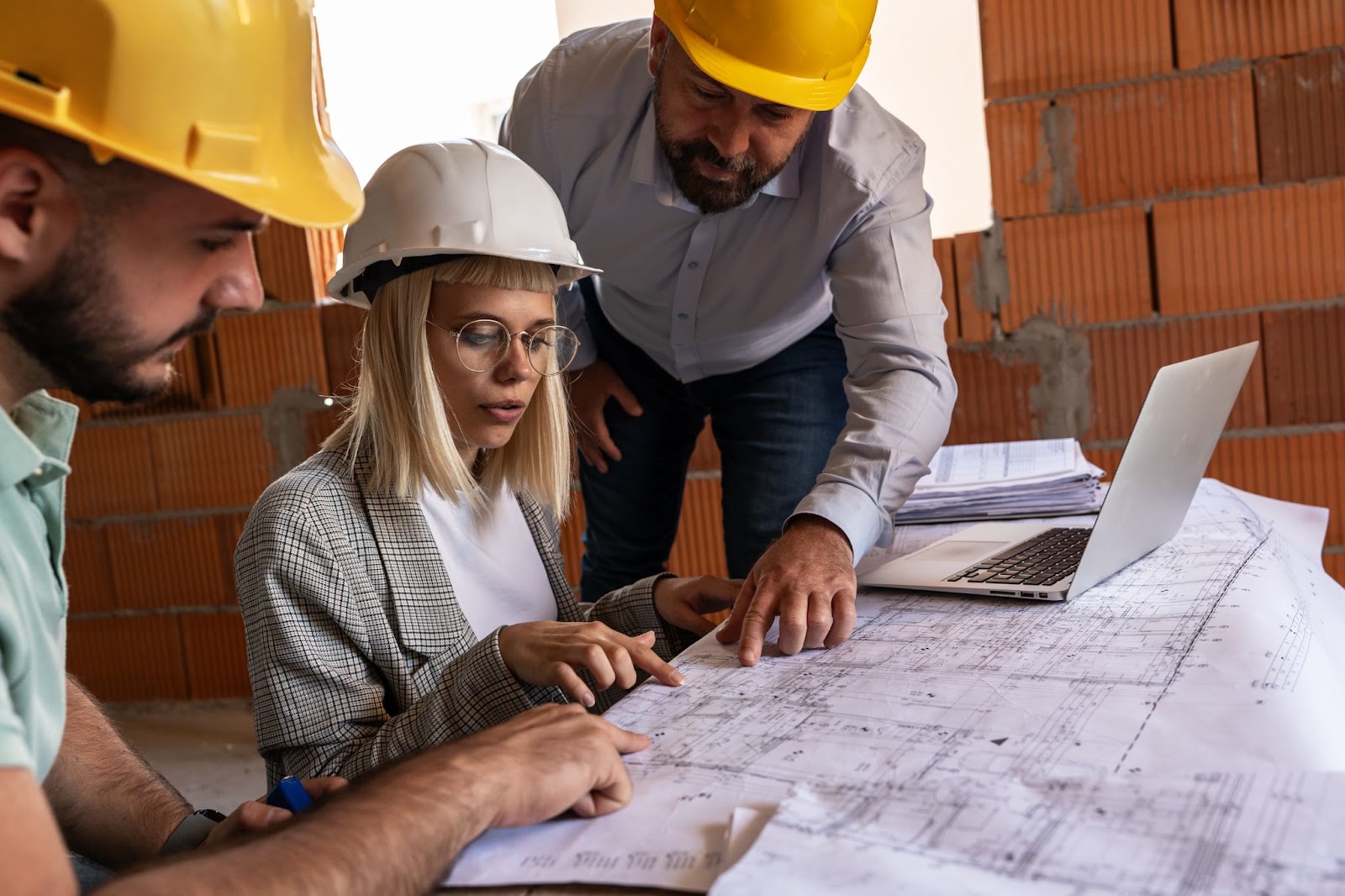 Male architects with a female construction manager analyzing the blueprint.