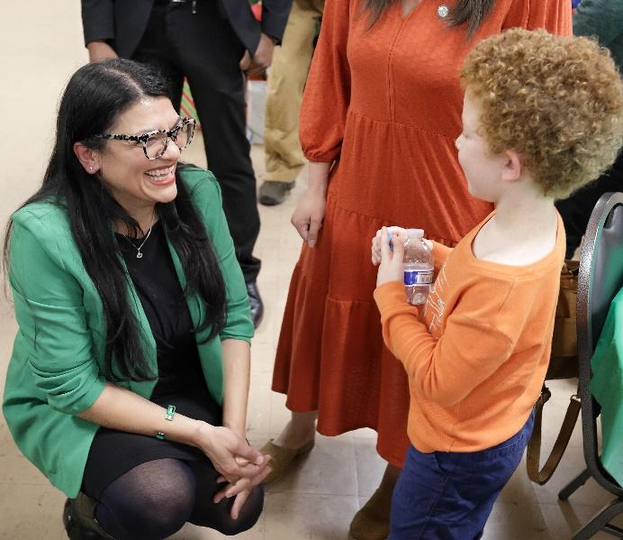 Rashida kneels to speak to a young supporter