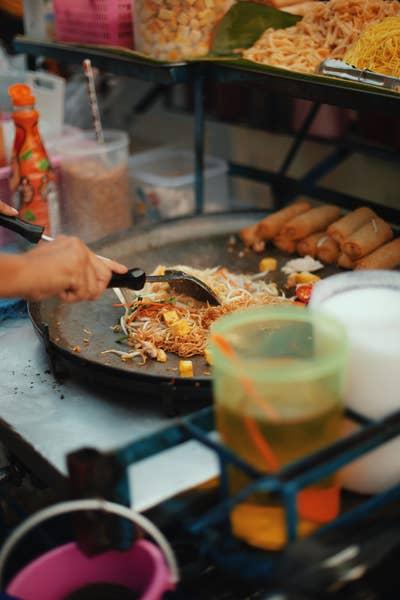 Someone cooking pad Thai in a hawker stall.