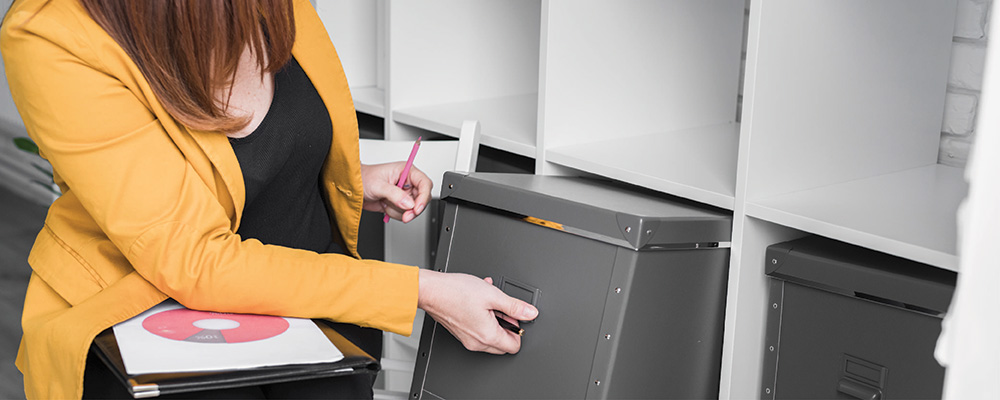 A businesswoman going through various files in a storage box
