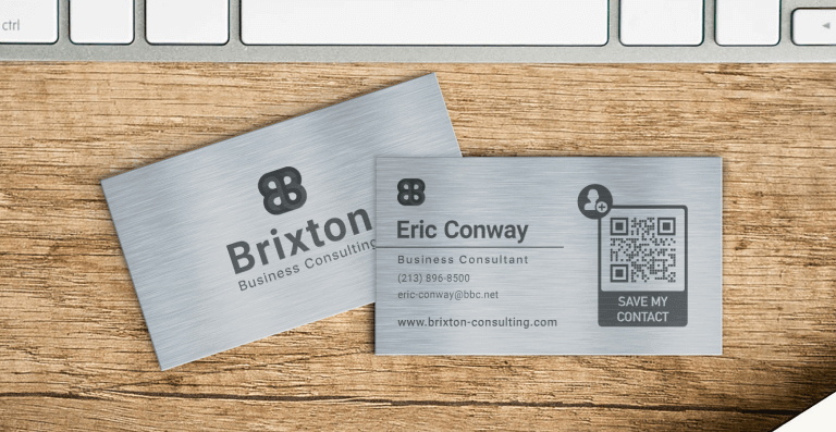 Eric Conway at Brixton Business Consulting’s metal QR Code vCard is displayed on both sides of the surface of a wooden table.