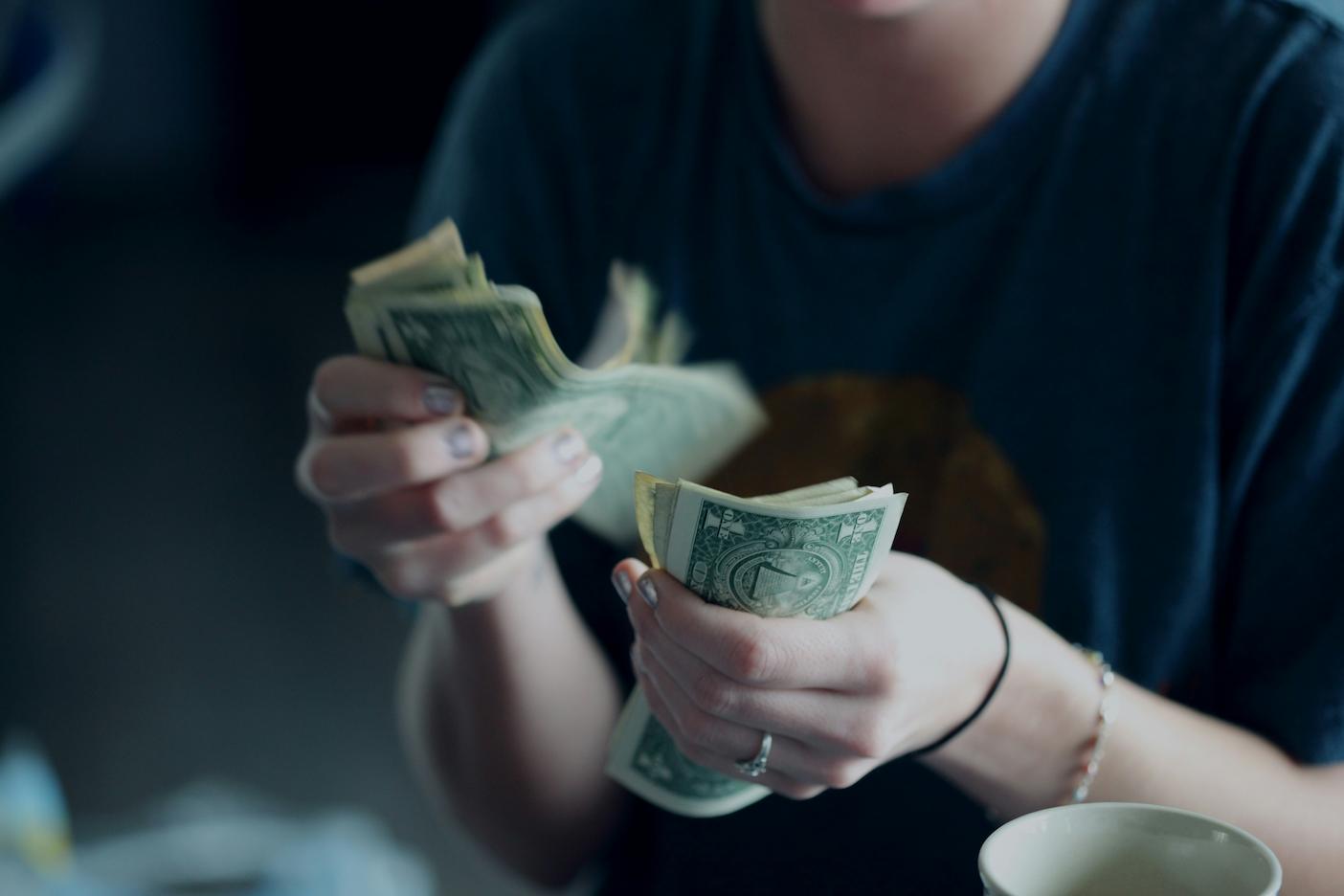 A woman counting money. Budgeting effectively is the backbone of organizing a successful seminar with mental health motivational speakers.