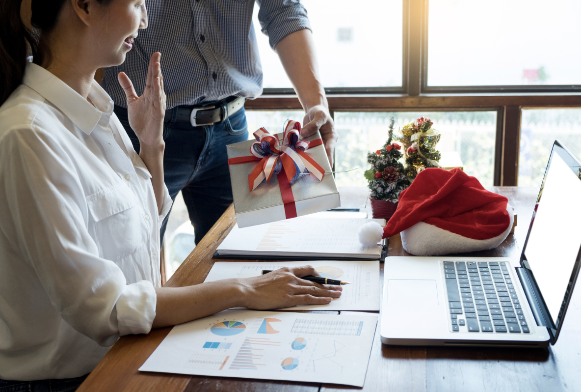 Colleague giving gift to woman in the office