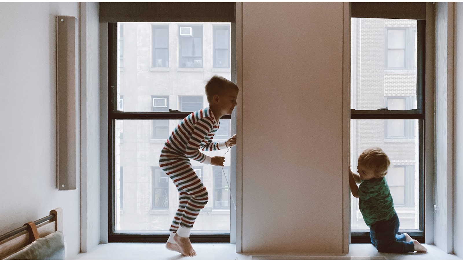 Children playing near the window on an upper floor apartment unit