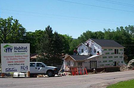 External photograph of a house under comstruction with a "Habitat fo Humanity" outside of it.