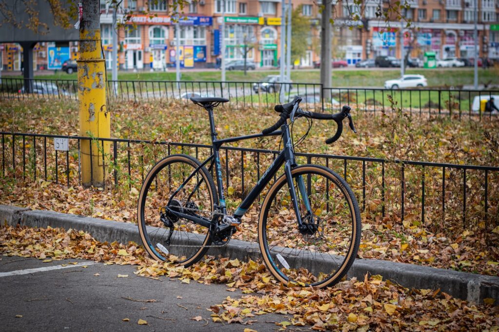 a bicycle parked on the side of a road next to a fence