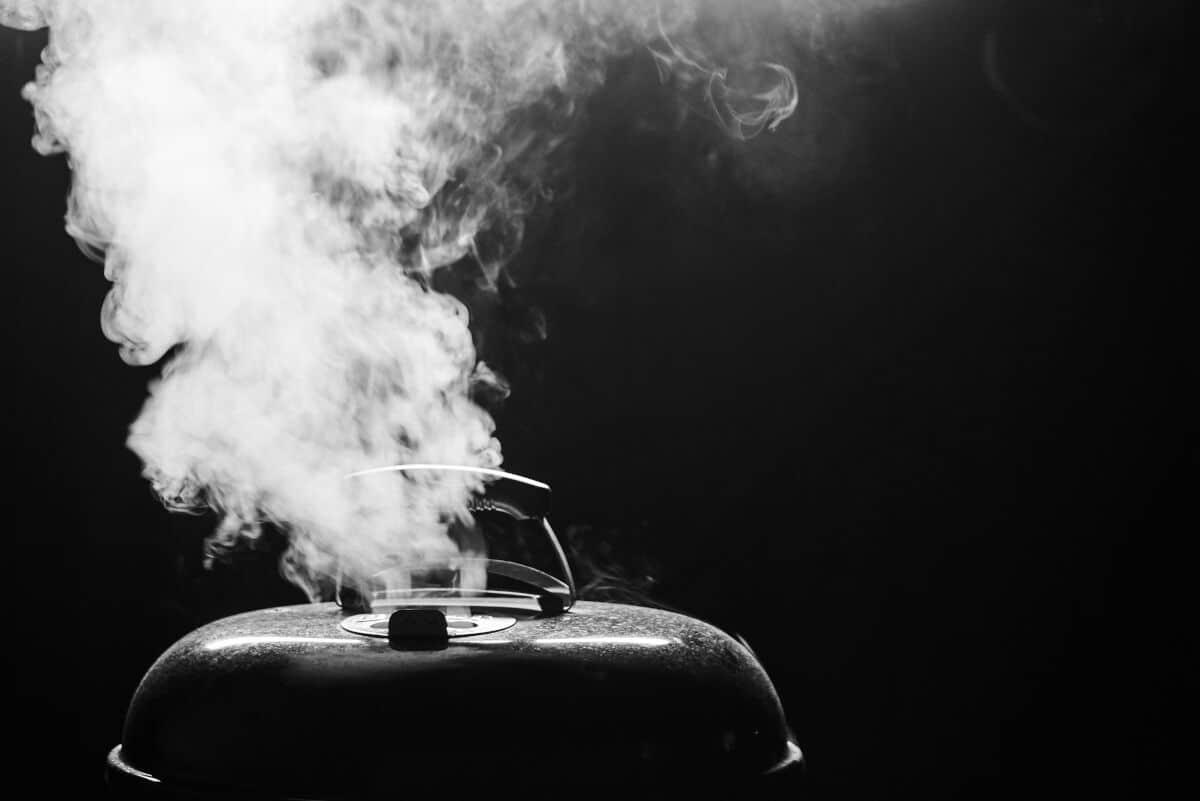 O imagine întunecată a unui grătar cu fum care iese din aerisirea de sus