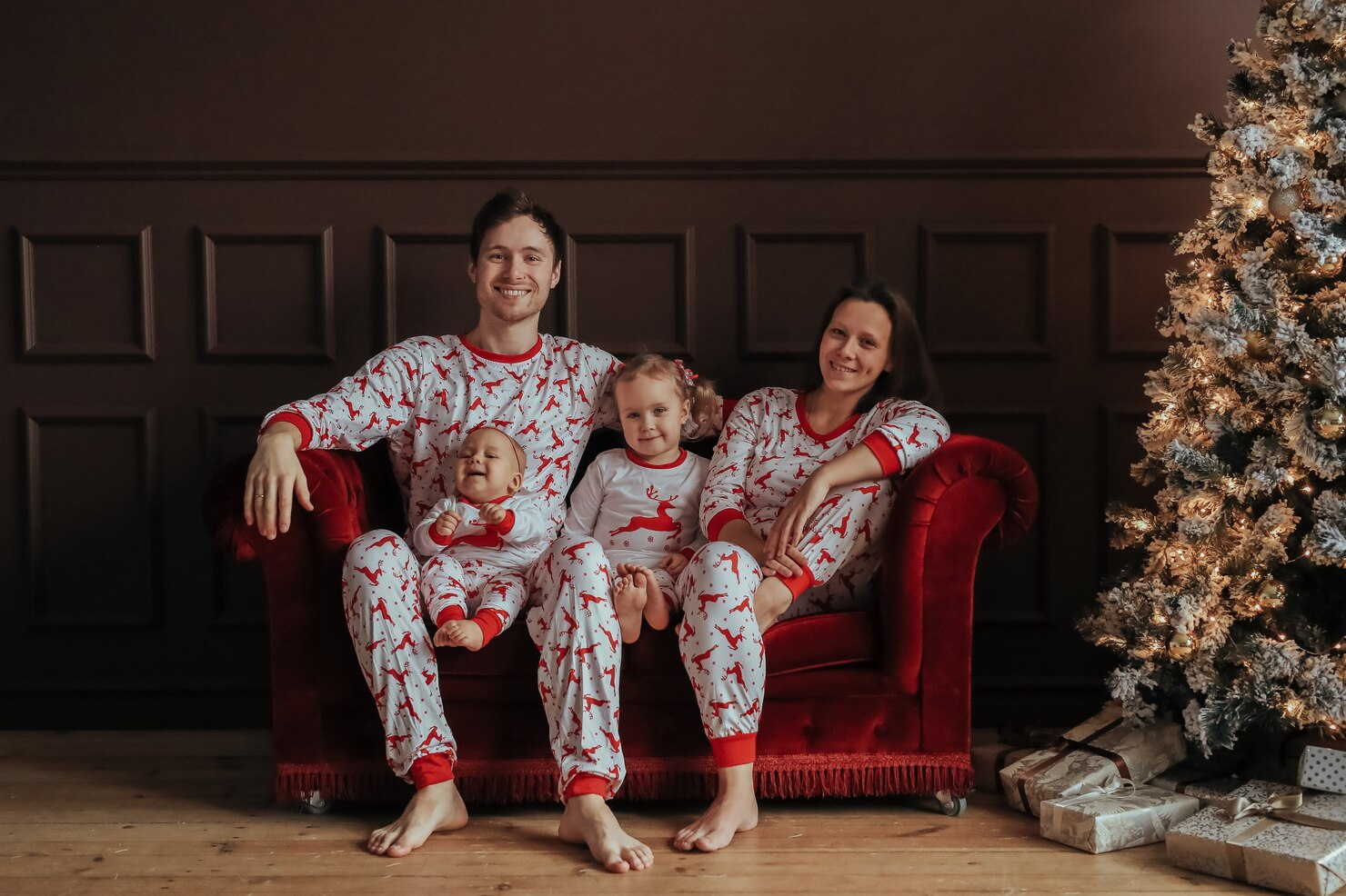 A family smiling for a picture in matching Christmas pajamas.