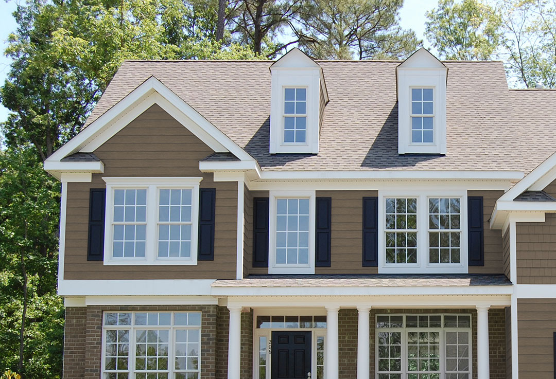 A composite cladding system covering the upper part of an American-style home