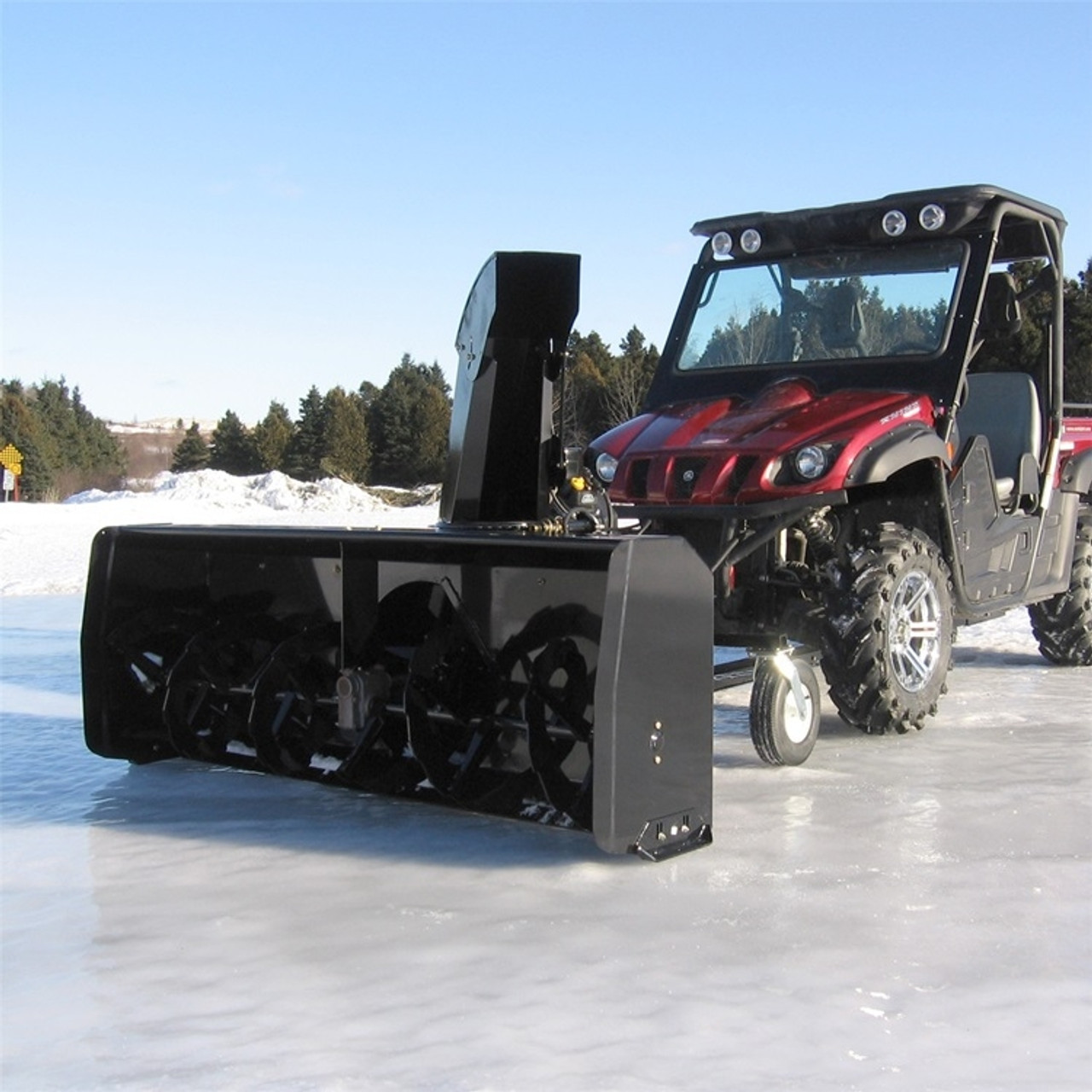 A front-oblique image of a Kubota RTV Snowblower by Bercomac, installed on a UTV and parked on icy terrain. 