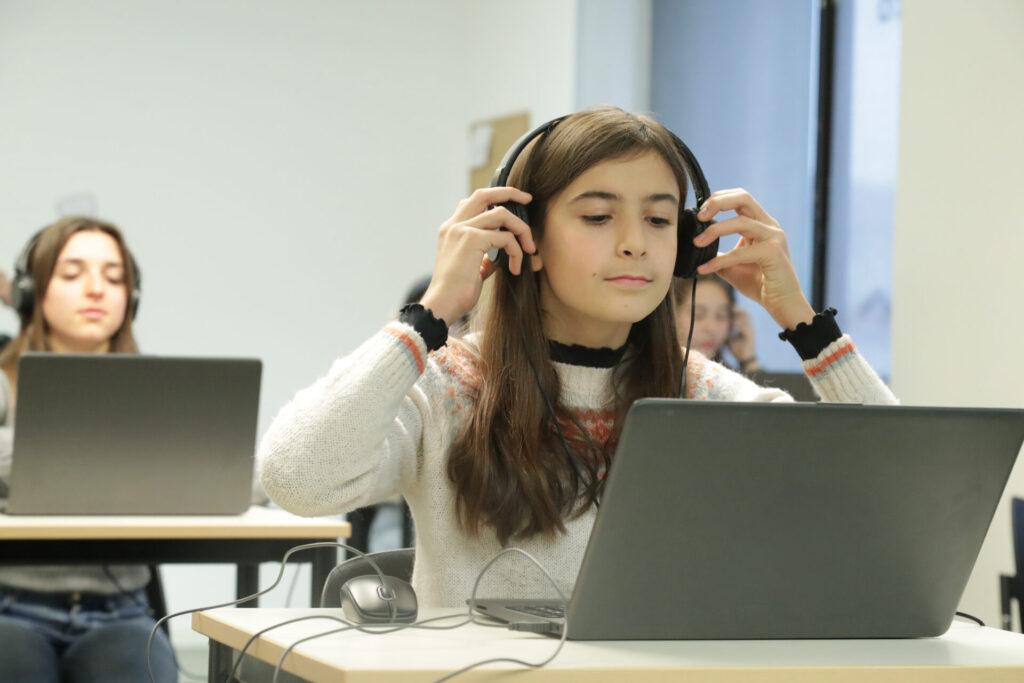 Mujer sentada frente a una computadora Descripción generada automáticamente