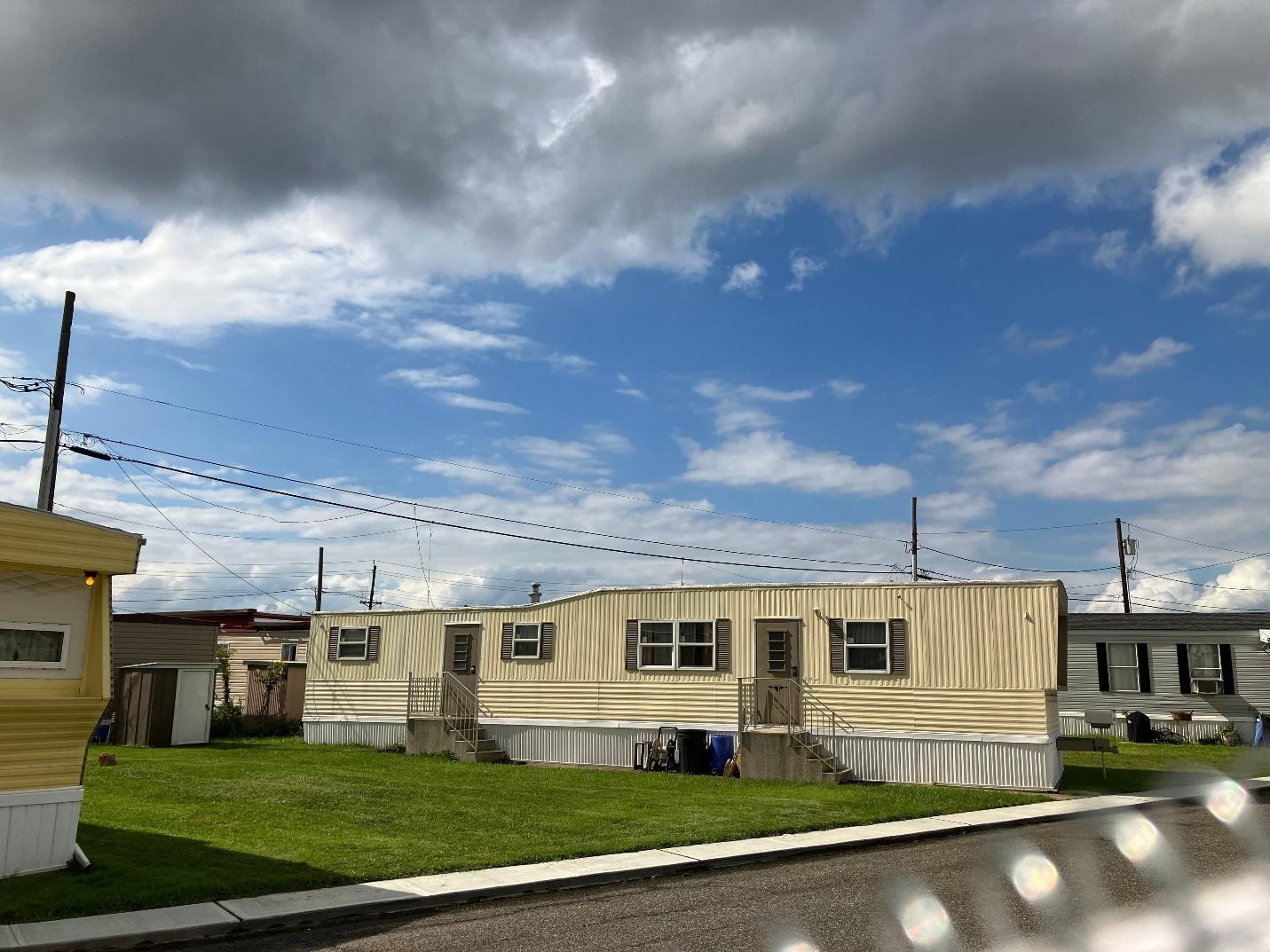 A mobile home with a lawn and power lines

Description automatically generated