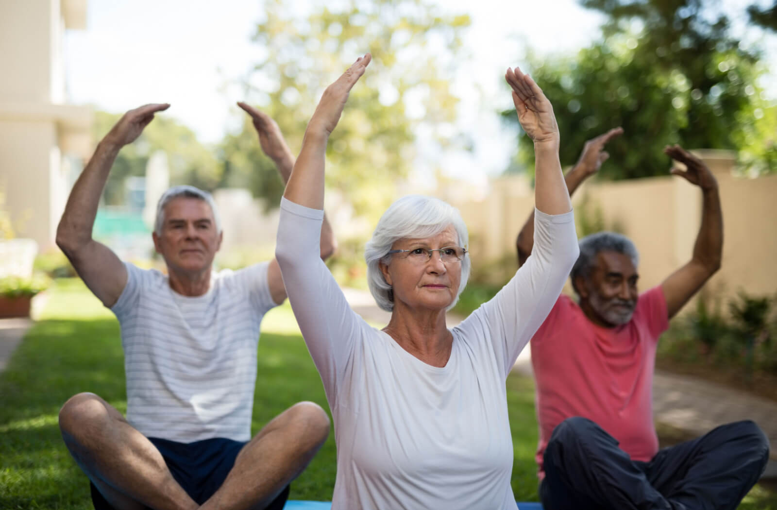 A group of older adults participating in a yoga class outdoors in their independent living community.