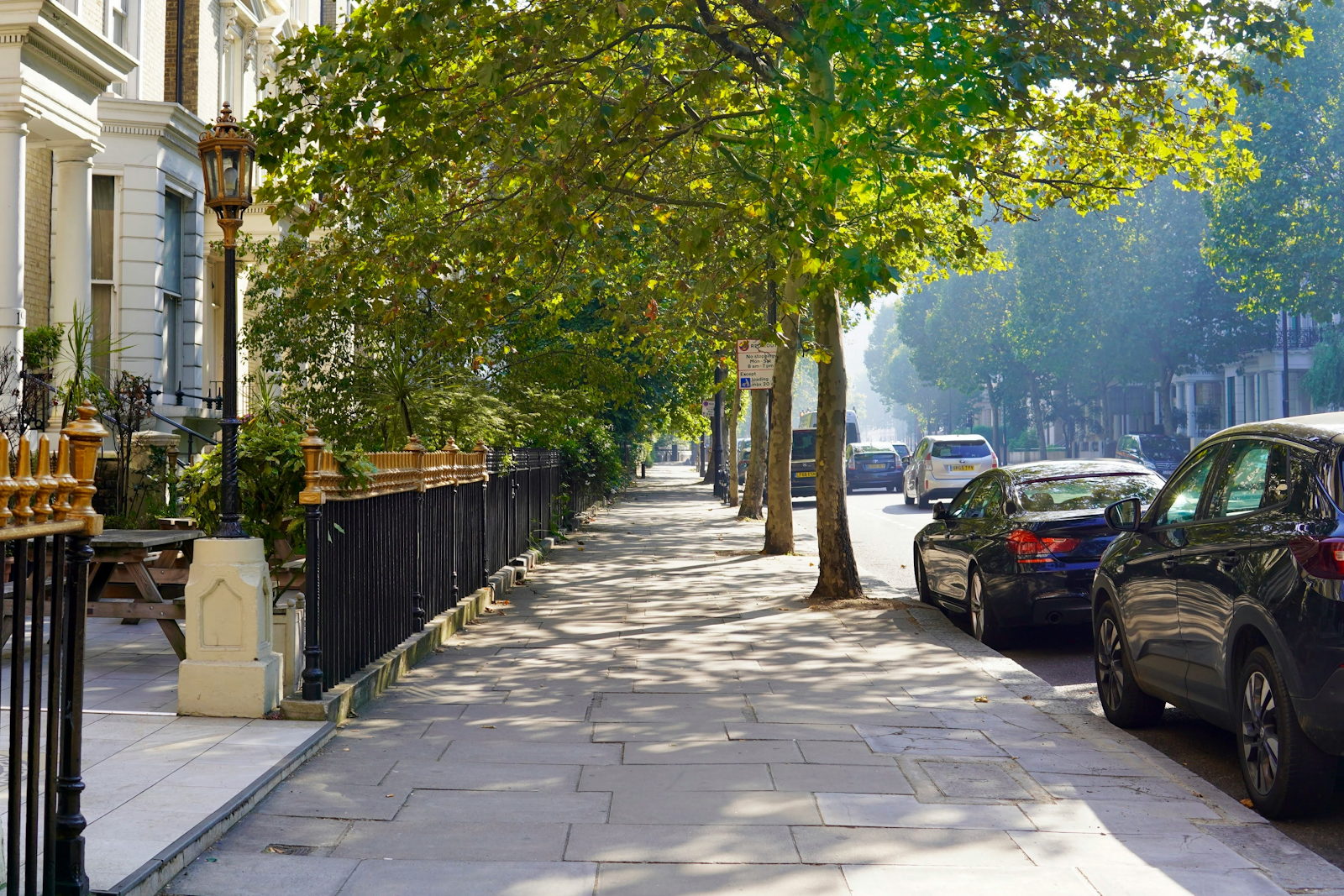 Residential city sidewalk lined with trees.