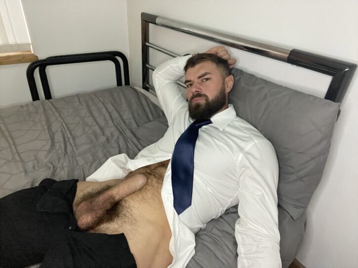 alpha bayton lying on the bed with his pants pulled down to reveal his hairy bush and erect dick