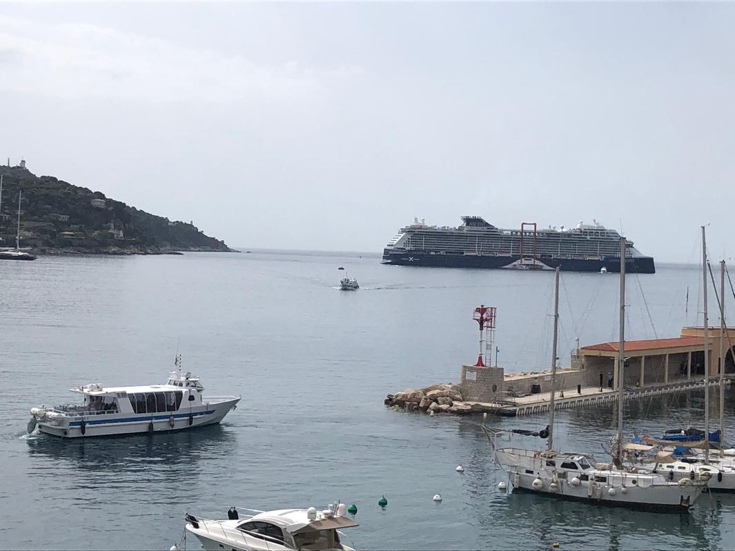 Boats in the water with a cruise ship in the background

Description automatically generated