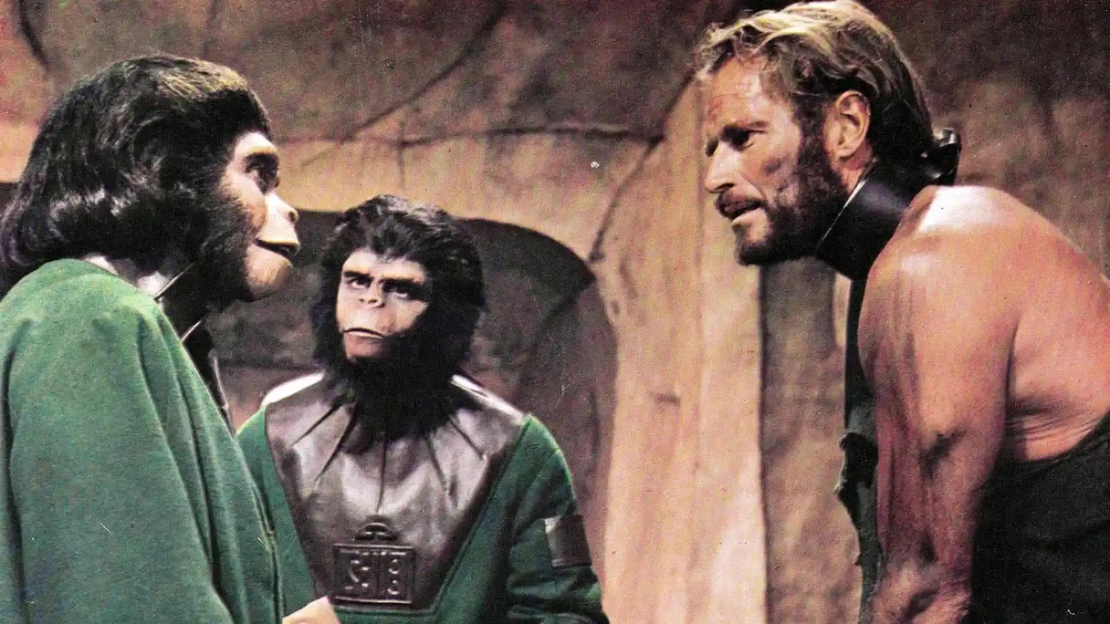 El personaje de Charlton Heston, encadenado desde el cuello, mirando a una simia vestida con una túnica verde