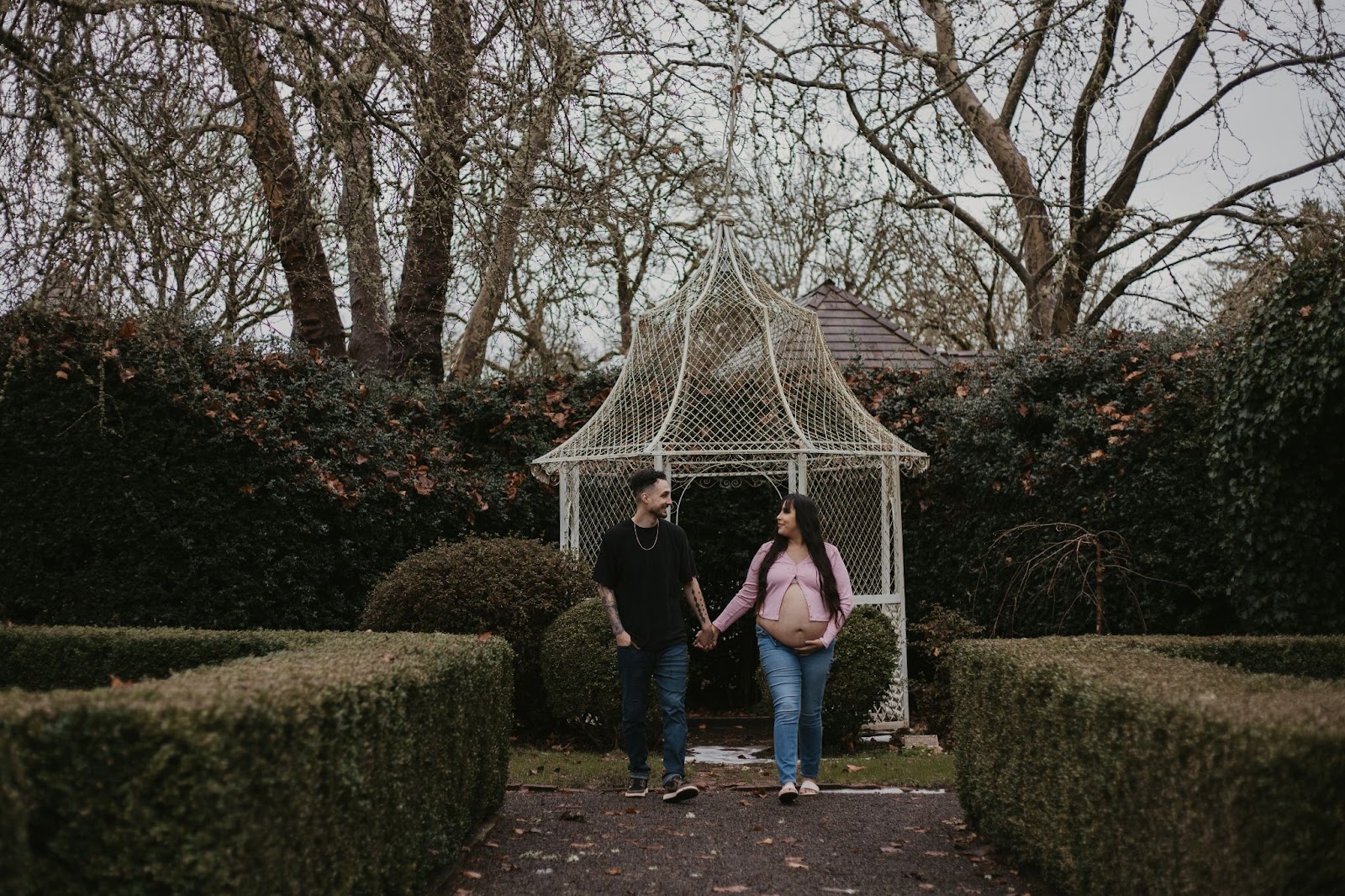 Pregnant couple standing in front of gazebo at Deepwood Museum and Gardens posing for their maternity session.