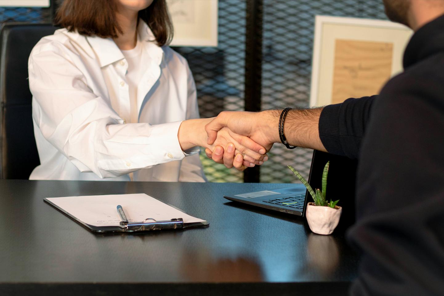 An event organizer shaking hands with a guest for an event with mental health motivational speakers.