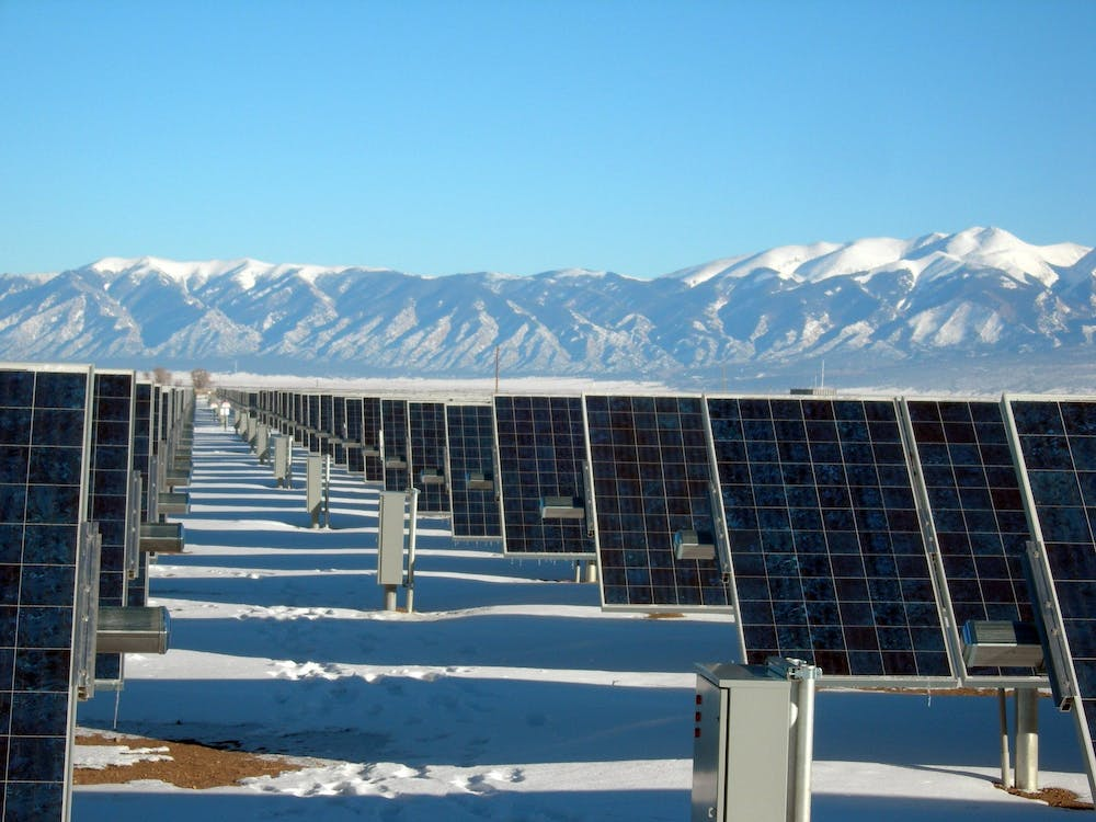 Solar panels on snowy surroundings, with mountains in the background