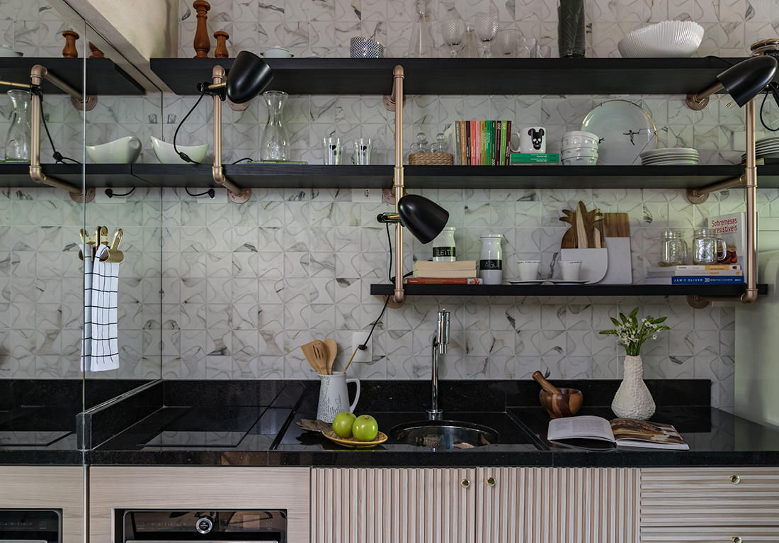 Foto de uma cozinha com decoração industrial. com vários canos metalizados sendo os suportes das prateleiras com louças aparentes, bancada da pia e prateleiras na cor preta.