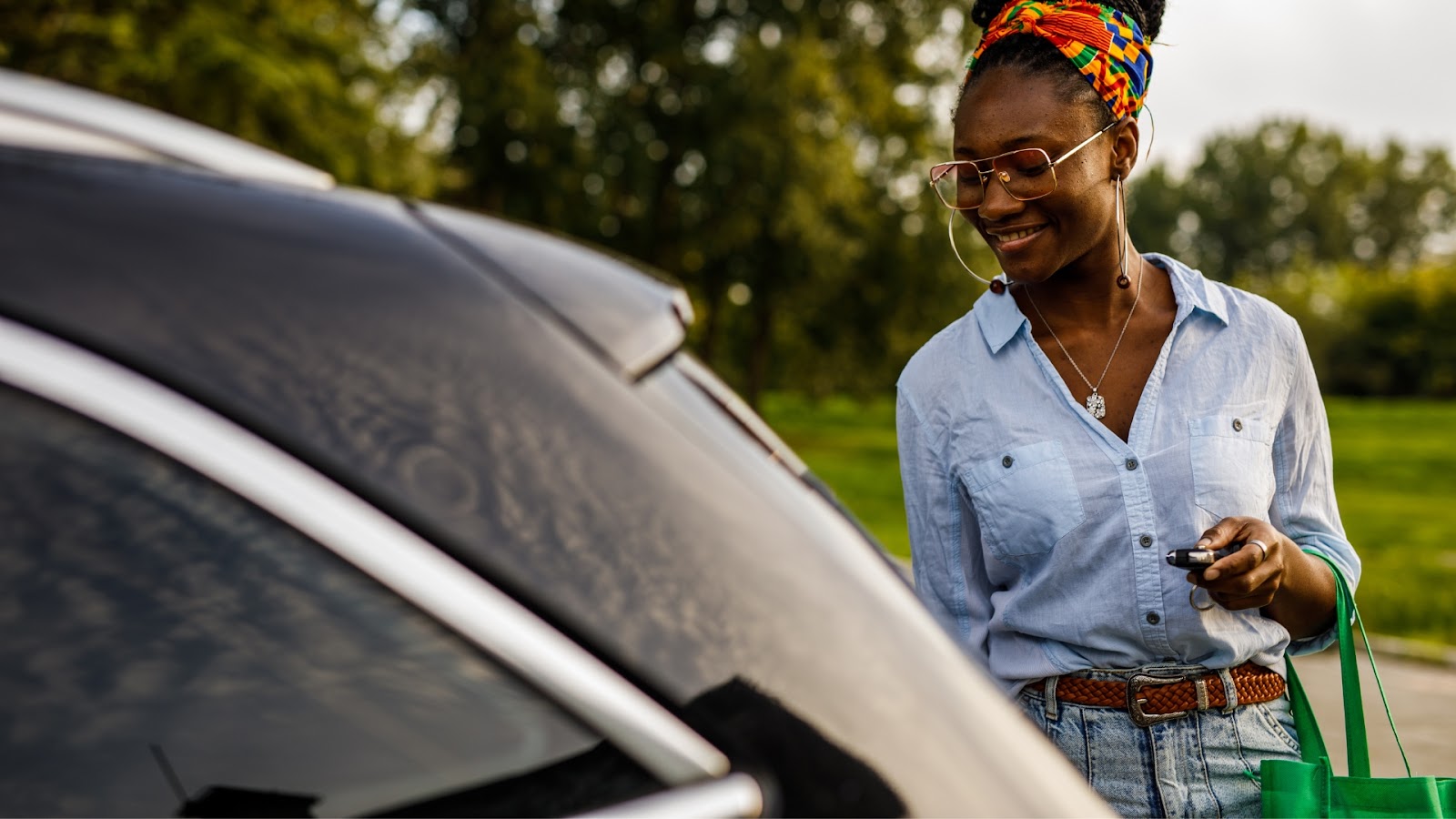 A cheerful woman stands by her car, holding the smart car key, ready to unlock the vehicle.