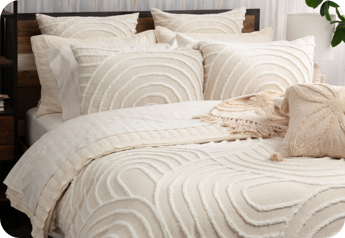 Notre housse de couette Sonrisa beige tuftée est présentée sur un lit avec des accessoires coordonnés.