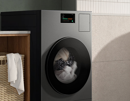 A Samsung Bespoke All-in-one washer dryer unit in use in a laundry room at home with a bamboo laundry basket next to it.