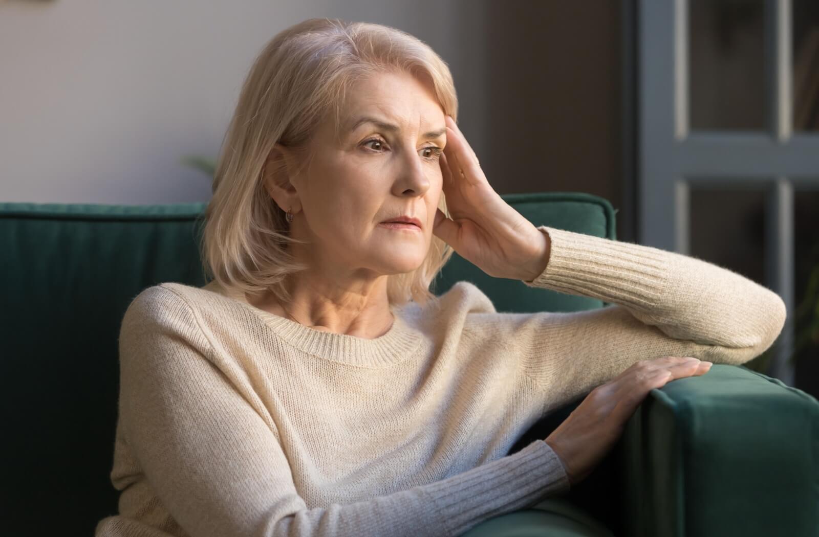 An older adult woman looking confused and anxious while staring at a distance.