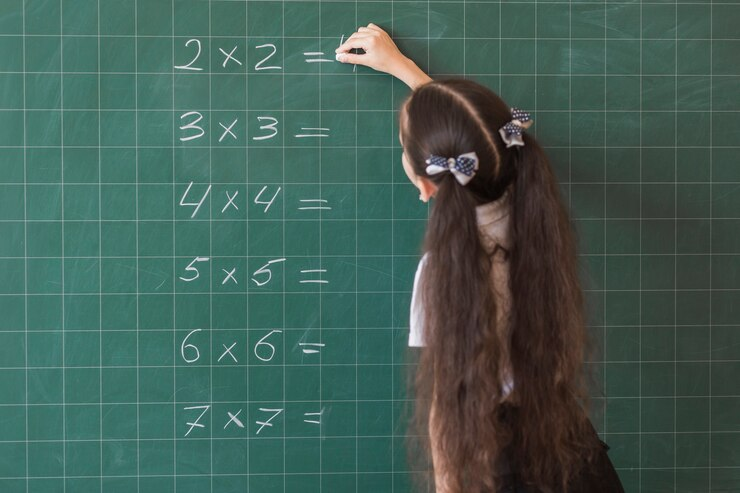 Focused student solving maths problems on a blackboard.