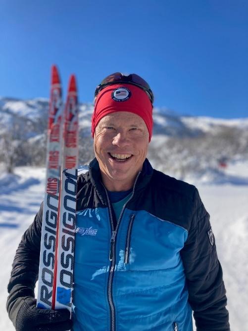 A person smiling with skis in the snow

Description automatically generated