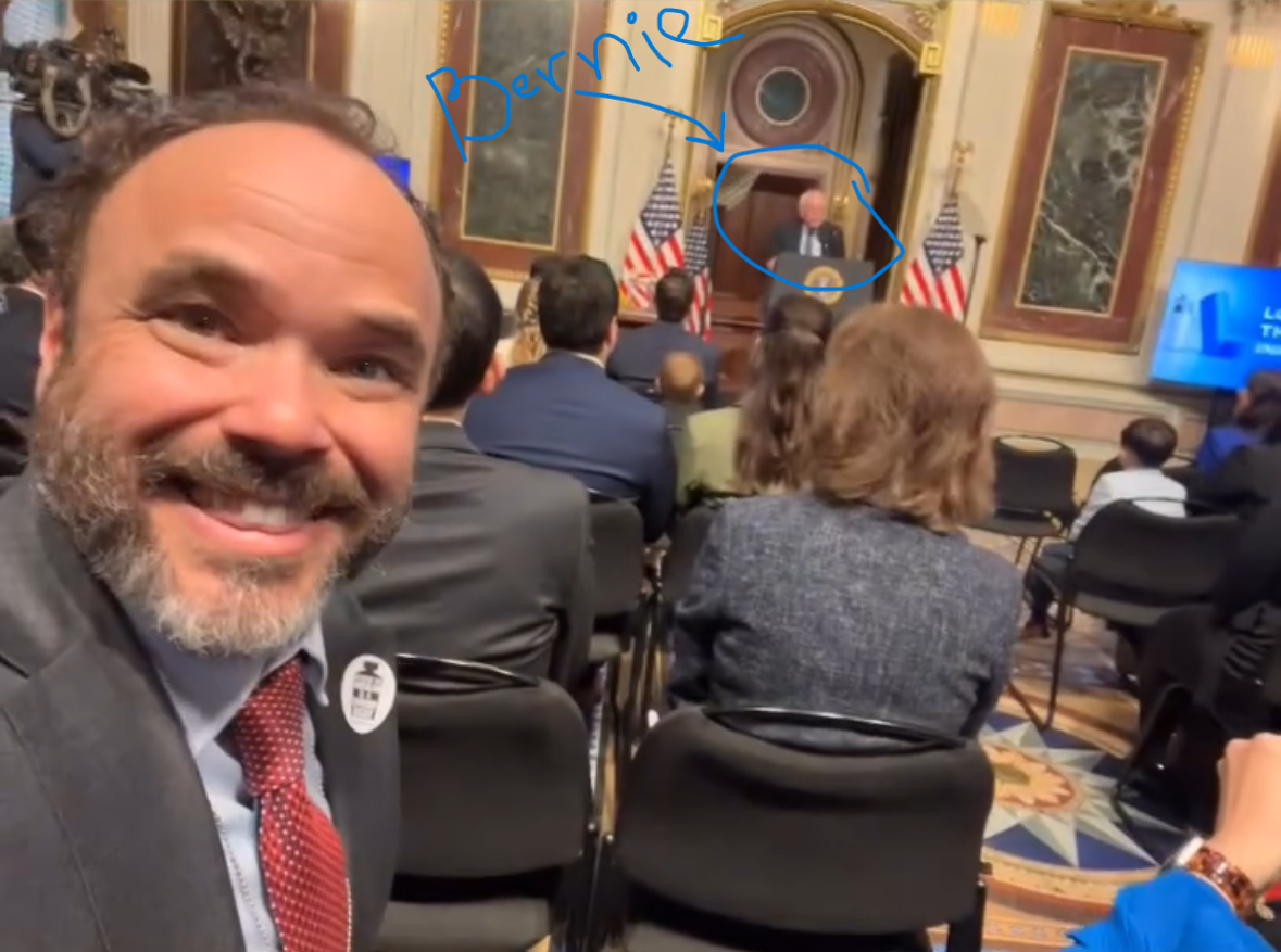 Selfie of Alex Lawson 4 rows away from Sen. Bernie Sanders speaking at the White House