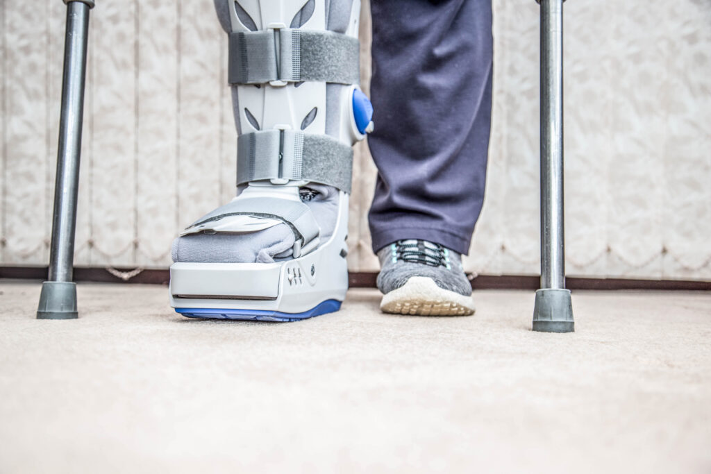 personal injury victim standing on crutches with a boot on their foot