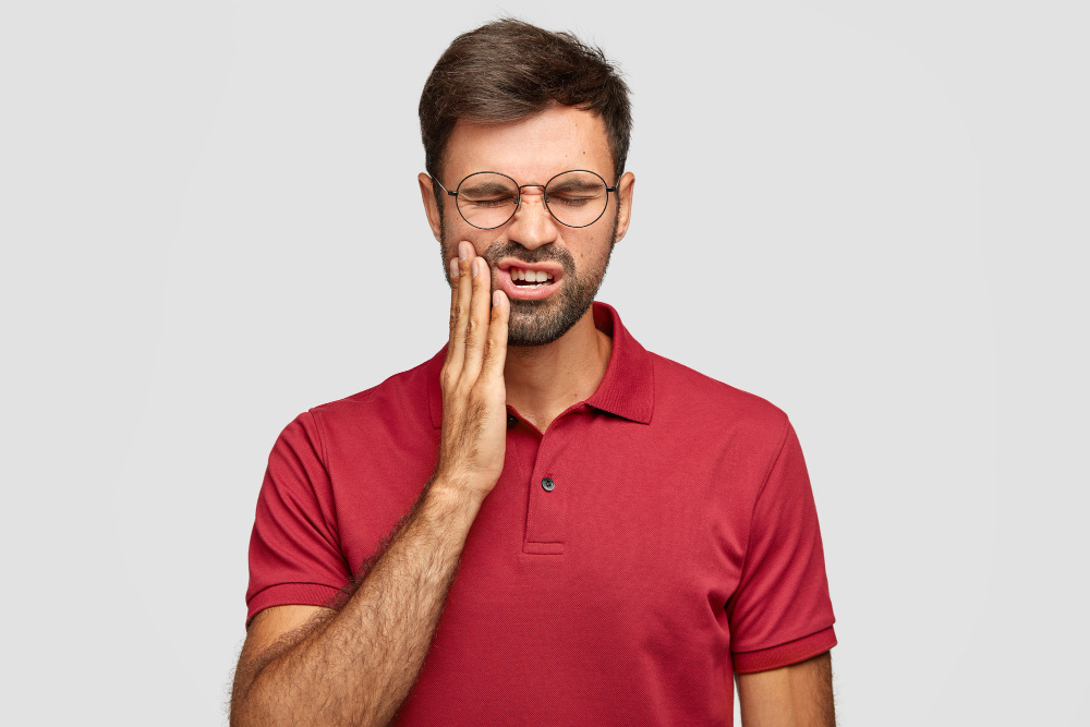 homem tocando a bochecha com dor de dente