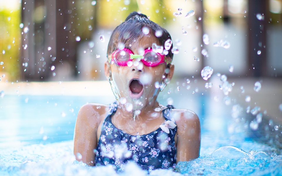 girl in pink goggles jumping out of water