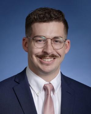 A person with mustache wearing glasses and a suit

Description automatically generated