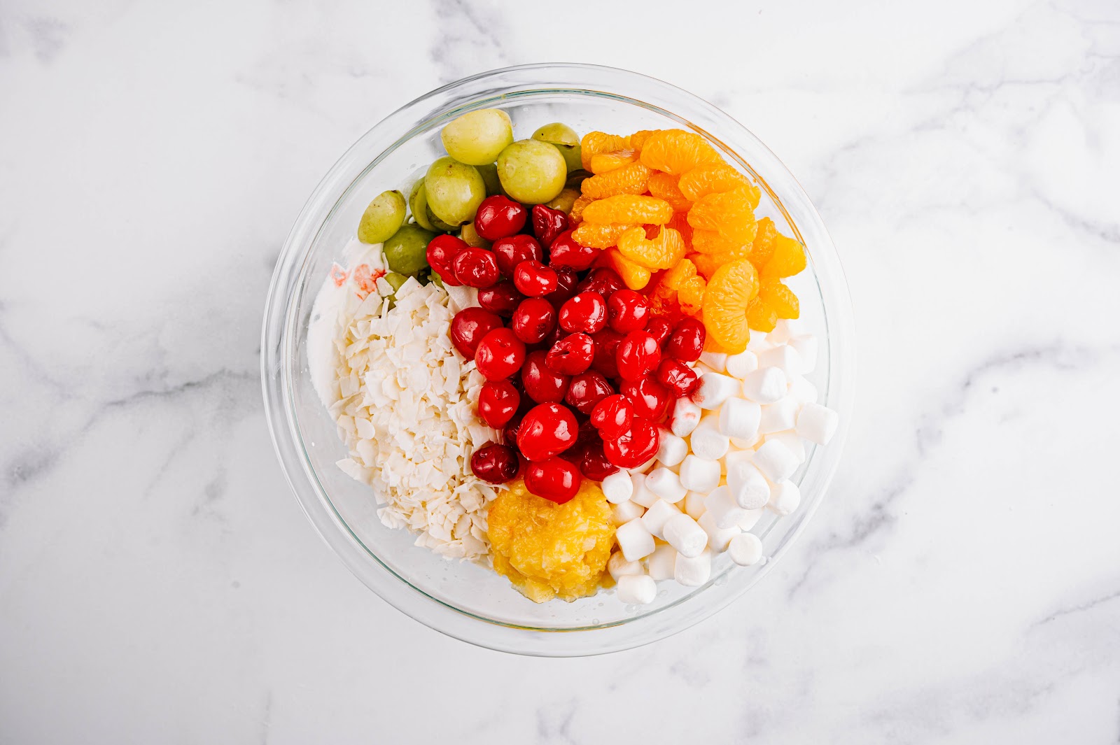 Put oranges, pineapples, cherries, marshmallows, and coconut in a serving bowl.