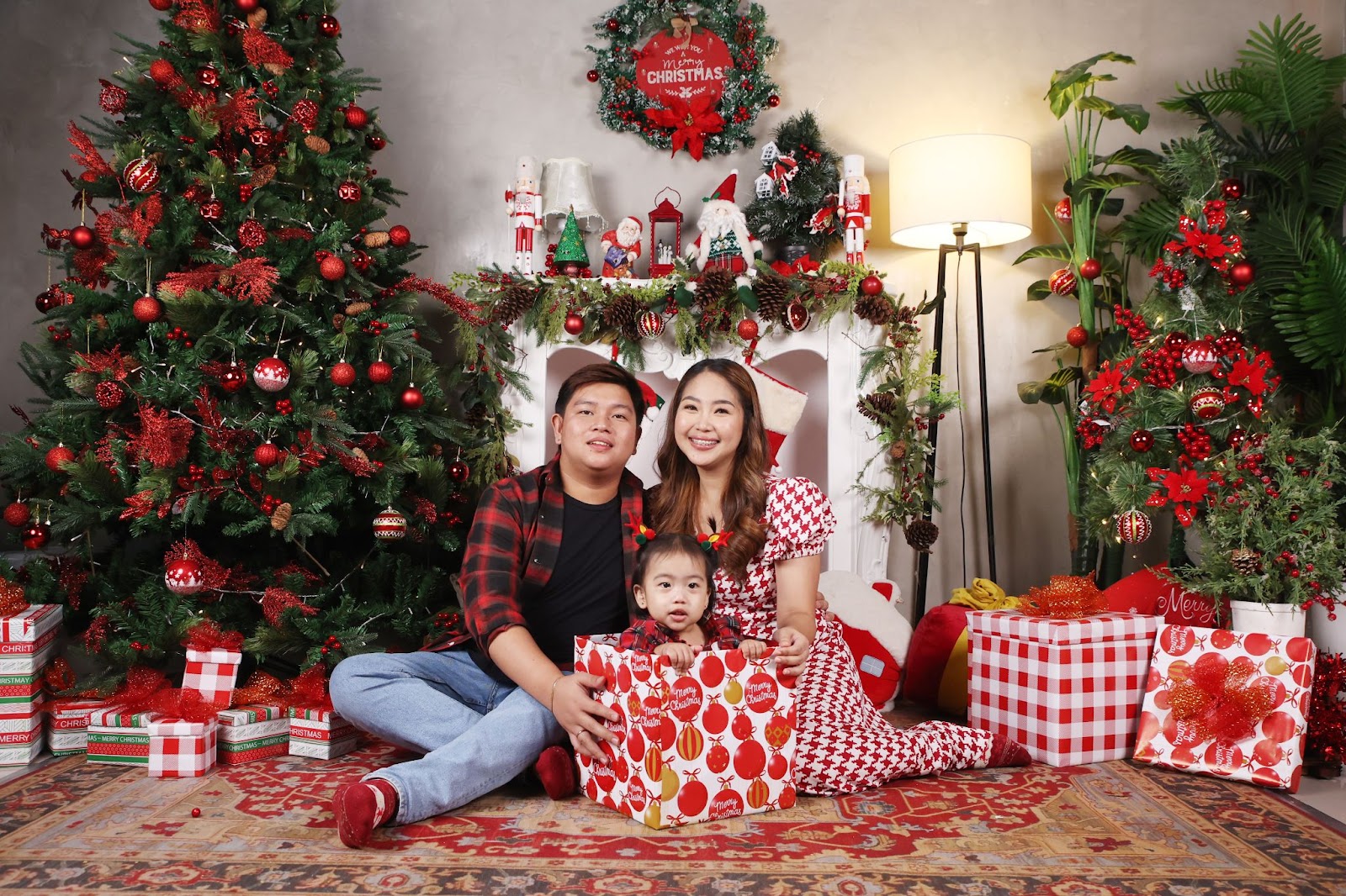 newborn christmas photo idea: baby inside the gift box posing with parents surrounded by Christmas decors