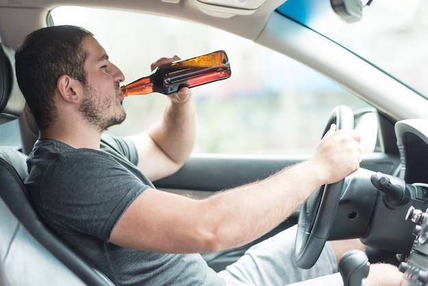 Man drinking beer in car