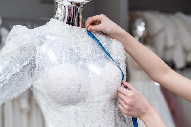 Premium Photo | Close up of female designer dressmaker hand fitting bridal  dress with measure tape in boutique