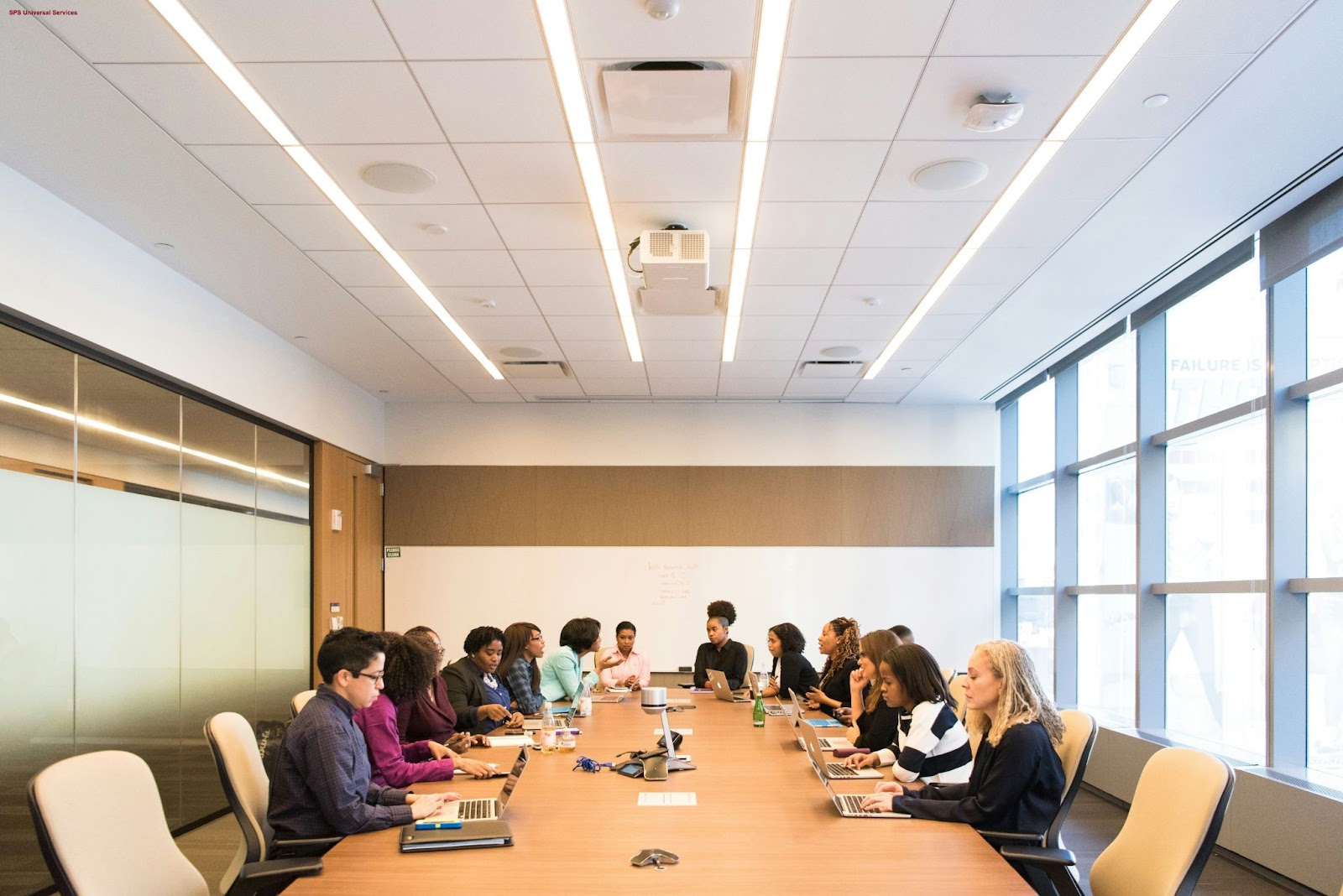 A group of employees participates in a training session around a conference table in a well-lit office space.