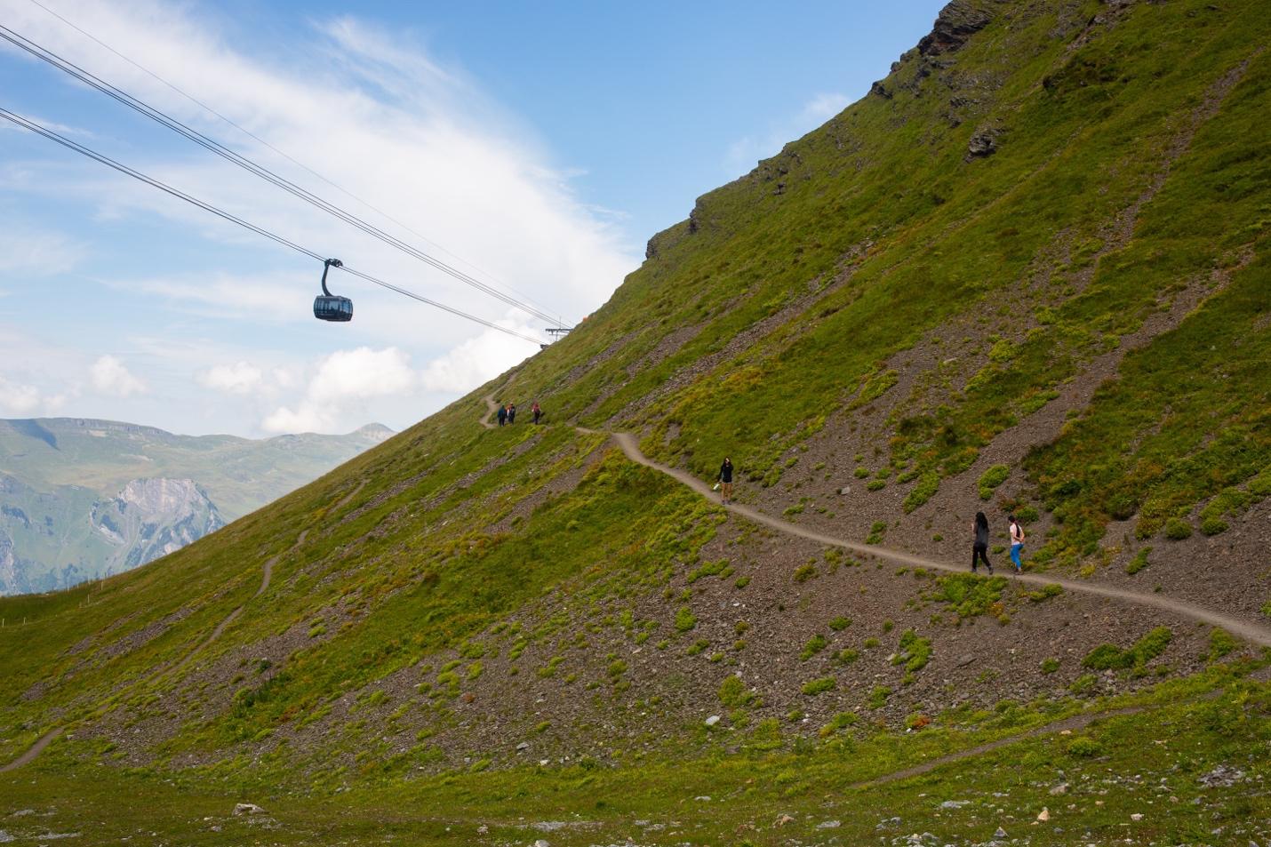 A group of people walking on a path on a hill

Description automatically generated