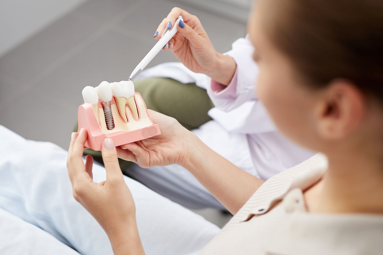 patient holding a teeth mould with a dental bridge with dentist pointing at the mould