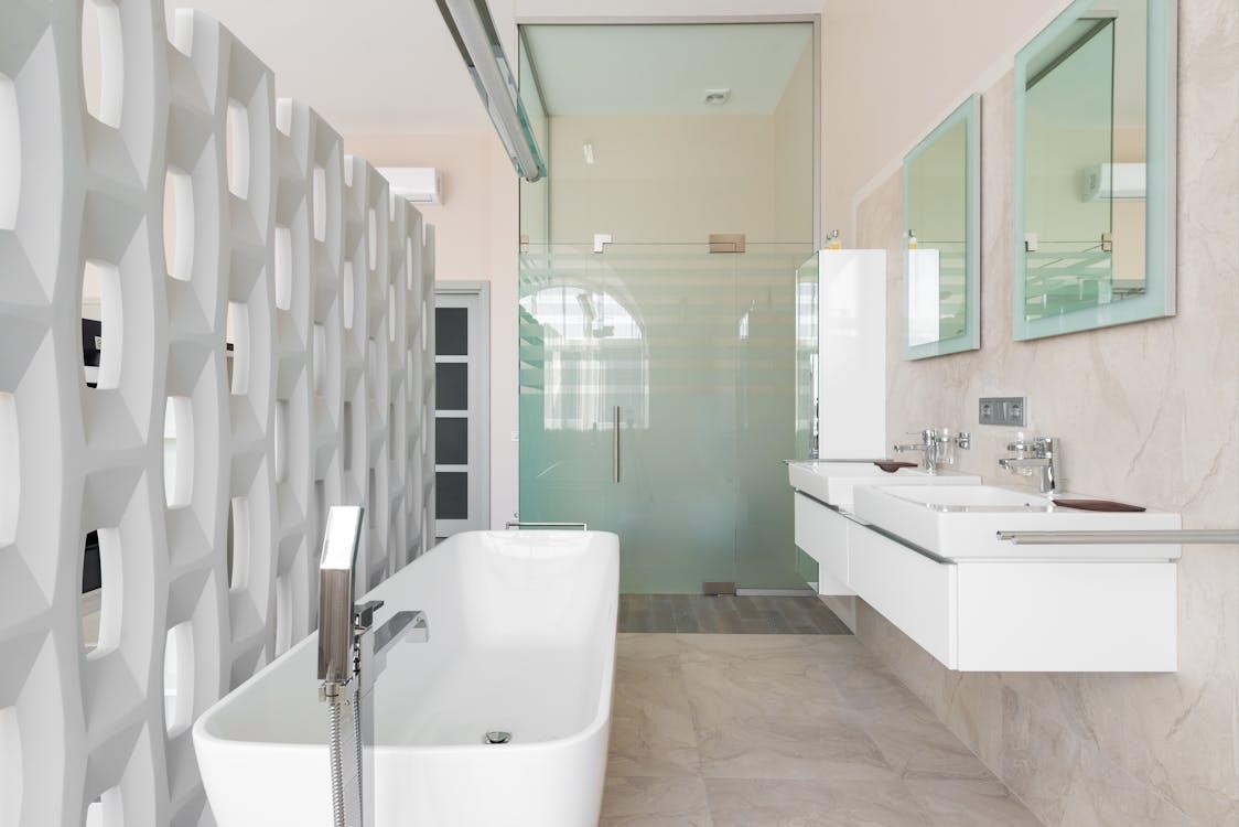 Free Modern bathroom with white bathtub and glass shower cabin and mirrors over basins Stock Photo